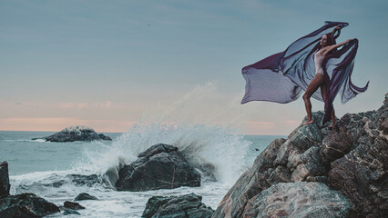 woman on the beach with wave crashing over rocks
