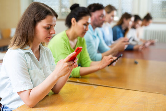 Portrait of adult students using mobile phones during lesson