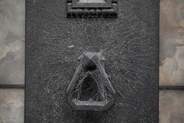 Detalles arquitect&oacute;nicos en cementerio aldaba de bronce con telara&ntilde;as