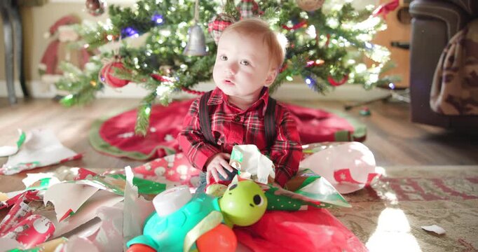 Baby Boy Eating Wrapping Paper Under Christmas Tree
