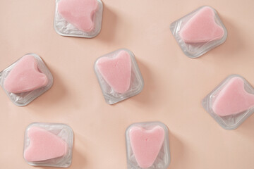 Many women's pink tampons stringless in individual package on beige background. New generation tampons for easy swim and freedom life. Hygiene accessories for women. View from above.