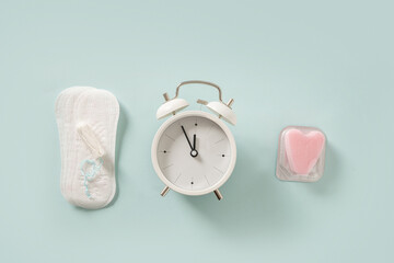 Female different tampons, daily pads, clock on blue background. Limited time use concept. Hygiene...