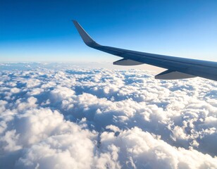 Obraz premium Soaring Above the Clouds: A captivating aerial perspective from an aircraft window, showcasing a fluffy expanse of clouds against a brilliant blue sky, symbolizing travel and freedom.