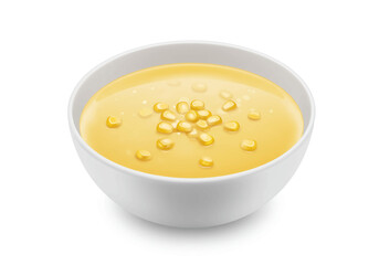 A white bowl filled with yellow corn soup and kernels sitting on a white background