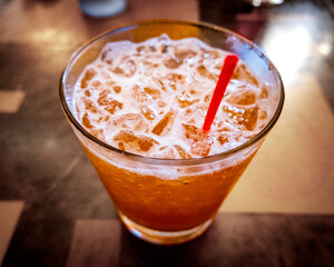 A classic chilled Mai tai cocktail served over crushed ice in a short glass, featuring a frothy orange hue and garnished with a red straw, set on a softly lit table.