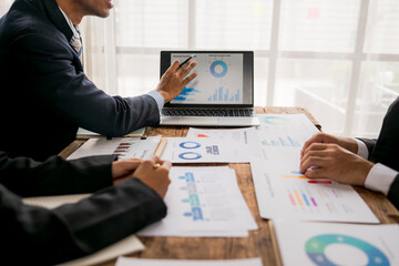 Business people analyzing charts on laptop and documents in office meeting