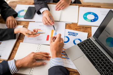 Business people analyzing charts and taking notes during corporate meeting