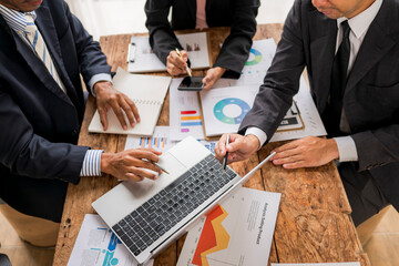Business people working on project using laptop and documents at office desk