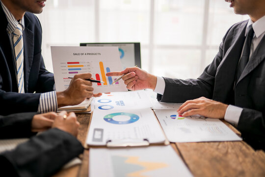 Business people analyzing statistics discussing financial results at office desk