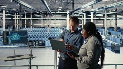 Server room coworkers use laptop to install updates and keep AI systems running. Data center engineering team uses notebook to write code improving infrastructure output, camera A