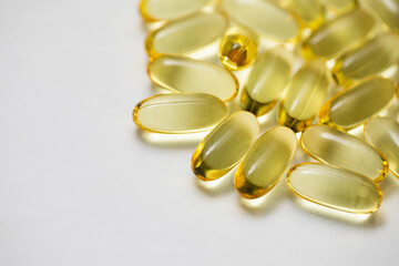 Closeup Omega-3 from Fish Oil yellow translucent clear soft gel capsule pills on corner of white background 