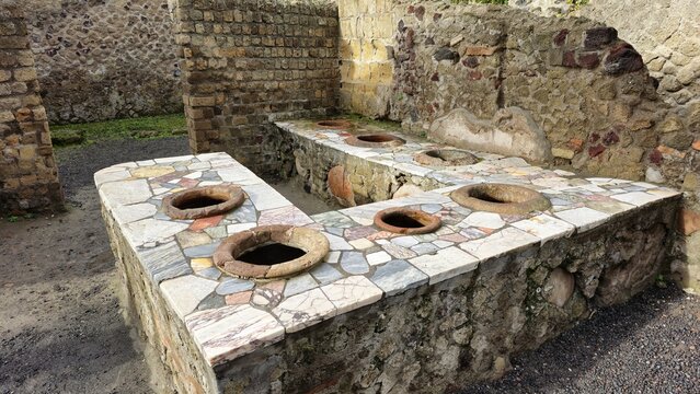 Herculaneum, Italy - 9 January 2025. Roman thermopolium with built-in dolia for storing hot food, set into a mosaic-covered stone counter.