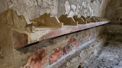 Herculaneum, Italy - 9 January 2025. Stone shelf with individual compartments in a Roman bath house, thought to store clothing and items during bathing.