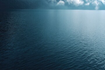 Obraz premium Calm lake surface reflecting a muted, overcast sky