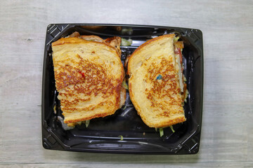 Picture of a grilled chicken sandwich on a sourdough bread served on a disposable plate.