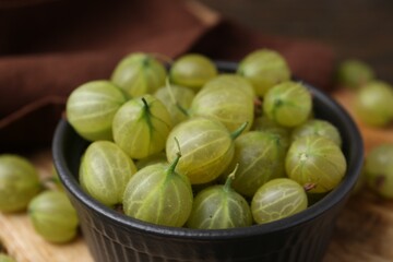 Fresh green gooseberries in bowl on table, closeup