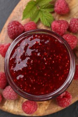 Sweet raspberry jam in glass jar and berries on table, top view