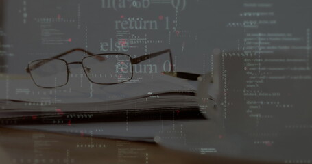 Displaying reading glasses resting on spiral notebook at home desk, with pen, mug, code overlay
