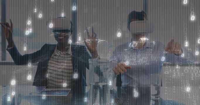 Two colleagues wearing blazers and VR headsets interacting in office meeting room, with tablet - Powered by Adobe