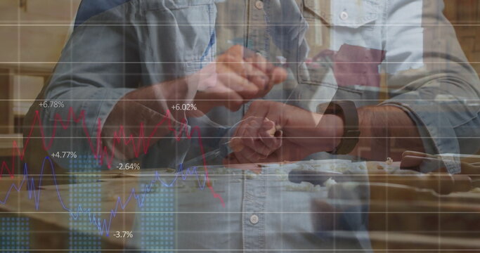 Carving craftsman in denim shirt using chisels and mallet in home workshop with finance graphs - Powered by Adobe