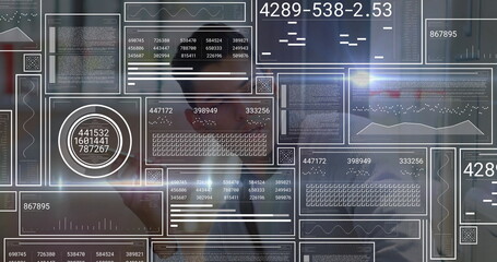 Interacting Hispanic man in suit adjusting floating digital panels at office, numeric dashboards