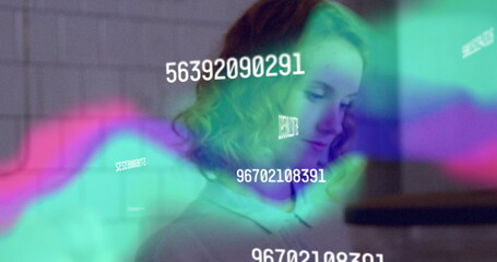 Curly-haired woman in collared shirt viewing data at workstation, with colored waveforms and codes
