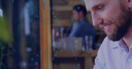 Smiling bearded man analyzing data overlay on tablet at workspace with wooden partition, copy space