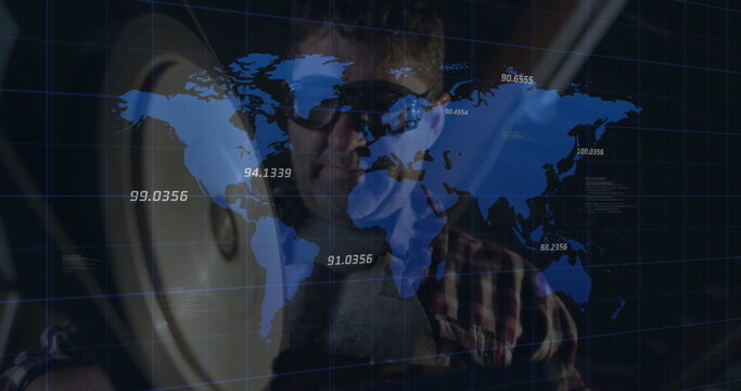 Technician wearing tinted glasses viewing digital world map in studio, speaker and coordinates