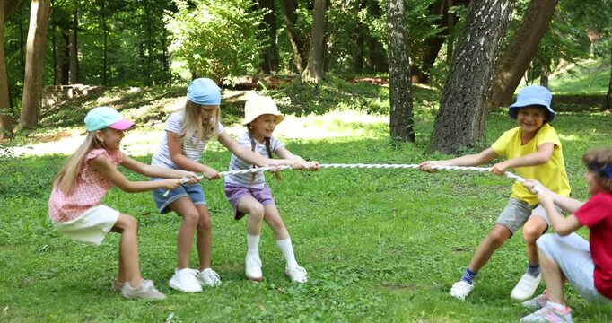 Cute little kids playing tug of war in park