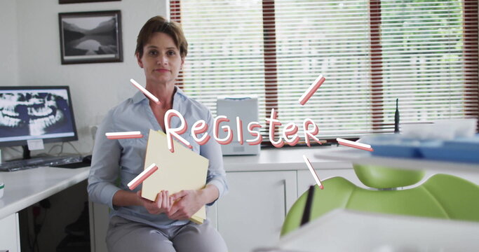 Receptionist in blue shirt organizing yellow patient folders at dental reception, with Xray monitor - Powered by Adobe