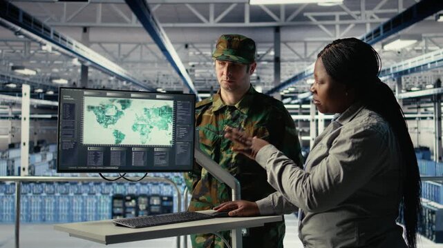 Team of military specialists in data center looking at world map on screen, coordinating mission zones. Army colleagues in server hub looking at global map to plan battlefield operations, camera A
