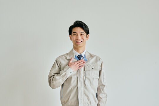 胸に手を当てる作業服姿の若い男性
