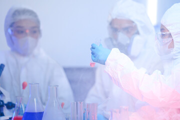 A diverse team of scientists collaborates in a high-tech biotech lab. A senior researcher mentors...