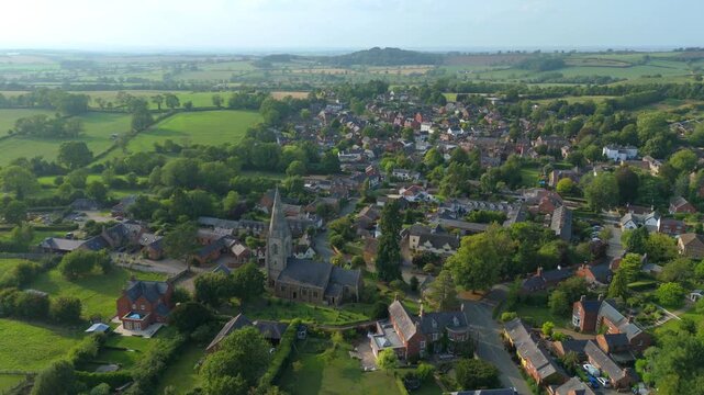 Aerial drone view over small quaint village in Leicestershire late evening light, houses and church, green rural landscape England UK European 