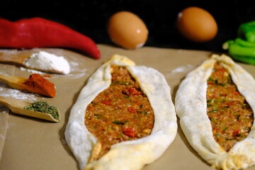 Making ground meat pide, a traditional Turkish culinary delight. A housewife prepares ground meat pide. Eggs, green and red peppers. Healthy eating. Making pide at home. Turkish cuisine.