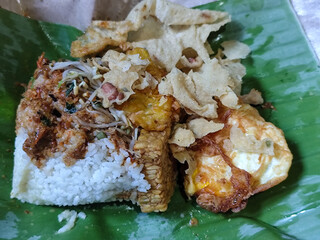 Nasi pecel or sego pecel is a typical Javanese Indonesian rice dish served with pecel sauce, which can be added with vegetables, peyek, eggs, tempeh and other side dishes. With basic ingredients of ba