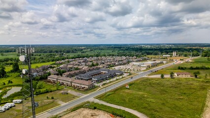 Drone view of cell tower next to suburban housing and green fields