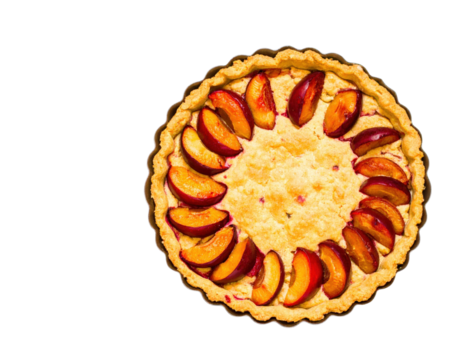 Freshly baked plum tart with sliced fruit in a circular pattern and a golden fluted crust.