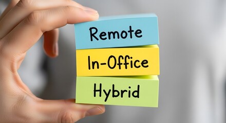 Hand holding a stack of colorful blocks with the words Remote, In-Office, and Hybrid, representing modern work-from-home and workplace models