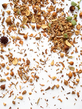 A scattered assortment of rant dried herbs and botanicals on a clean white background