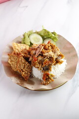 Ayam Geprek Indonesian crispy fried chicken with spicy sambal chili sauce, served with steamed rice, fried tempeh, and tofu, traditional Yogyakarta cuisine.