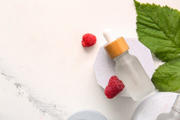 Decorative podium with bottle of cosmetic raspberry oil on white background