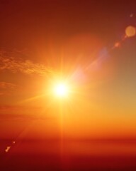 Naklejka premium A vibrant sunburst illuminates the horizon, casting a warm orange glow across the sky at sunset
