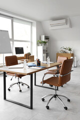 Interior of light conference hall with table computer, stationery and armchairs