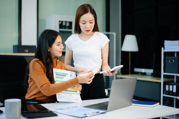 wo business women using laptop, standing and talking about analyzing documents in Teamwork Finance, Marketing