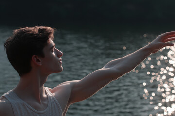 young man extends his hand towards shimmering water emphasizing intricate tendons and muscles in his arm
