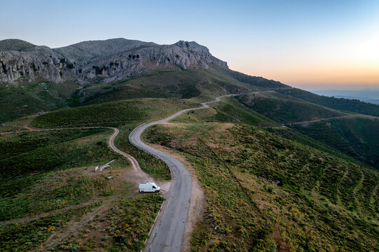 Aerial drone view of a white van parked on a winding mountain ro