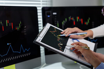 Businesswomen pointing at financial charts and graphs on clipboard, analyzing market trends and investment opportunities