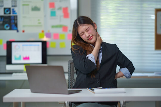 Asian office worker feeling discomfort from long hours of computer work, experiencing neck and back pain