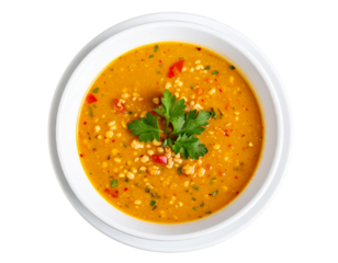 Thick orange lentil and barley soup with red pepper garnished with fresh parsley.